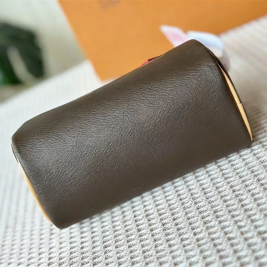 Brown textured leather cylindrical trunk bag for women, luxury designer handbag with smooth grain finish.