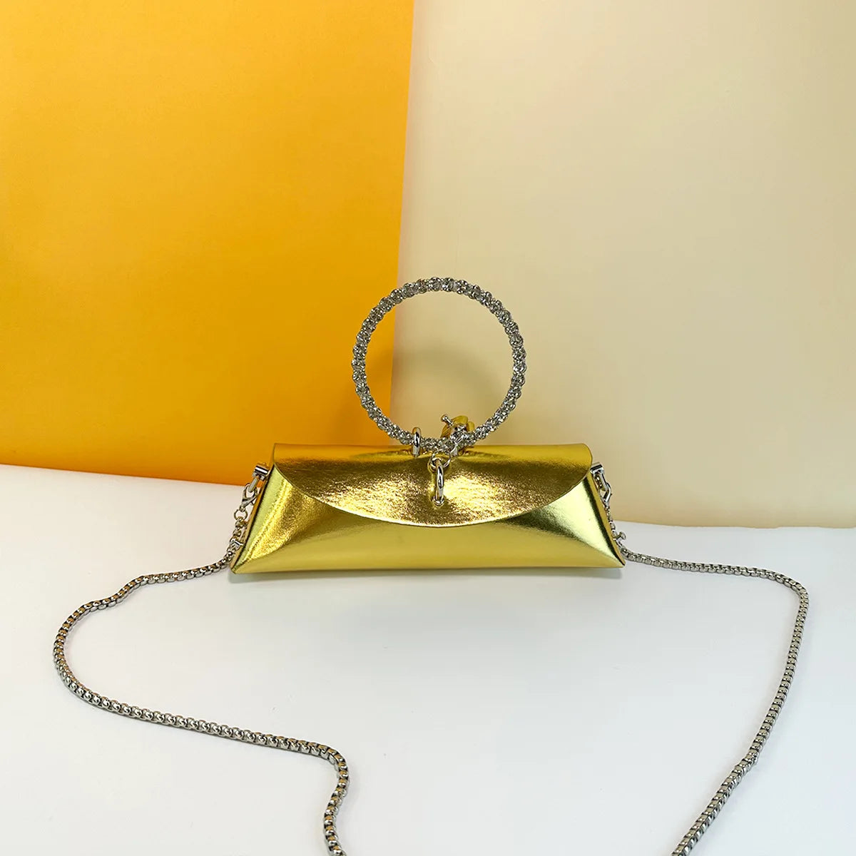 Gold metallic PU leather evening trunk clutch with crystal-embellished round metal handle and silver chain strap.