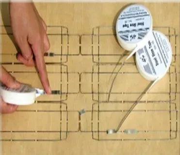 White shim tape roll sticking tape over a marked alignment grid on a board