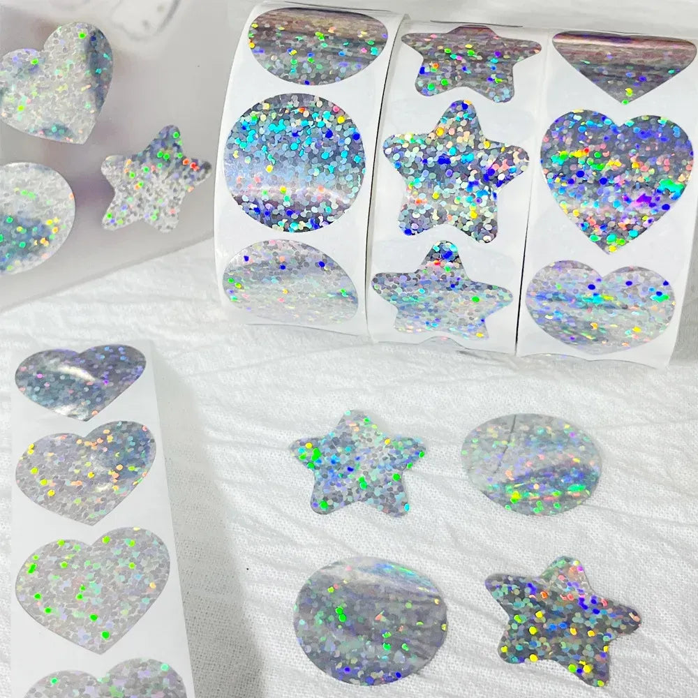 Holographic glitter heart, star, and badge-shaped stickers on clear backing sheet