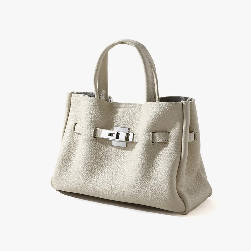 Cream pebbled leather handbag with silver lock clasp and top handles in a classic Old Money satchel design.