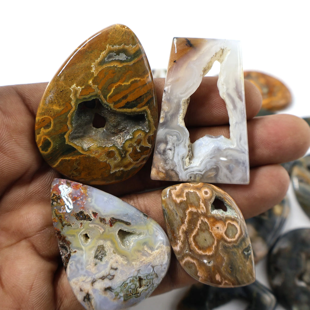 Ocean jasper cabochons in hand, teardrop and square shapes with brown and white layered patterns