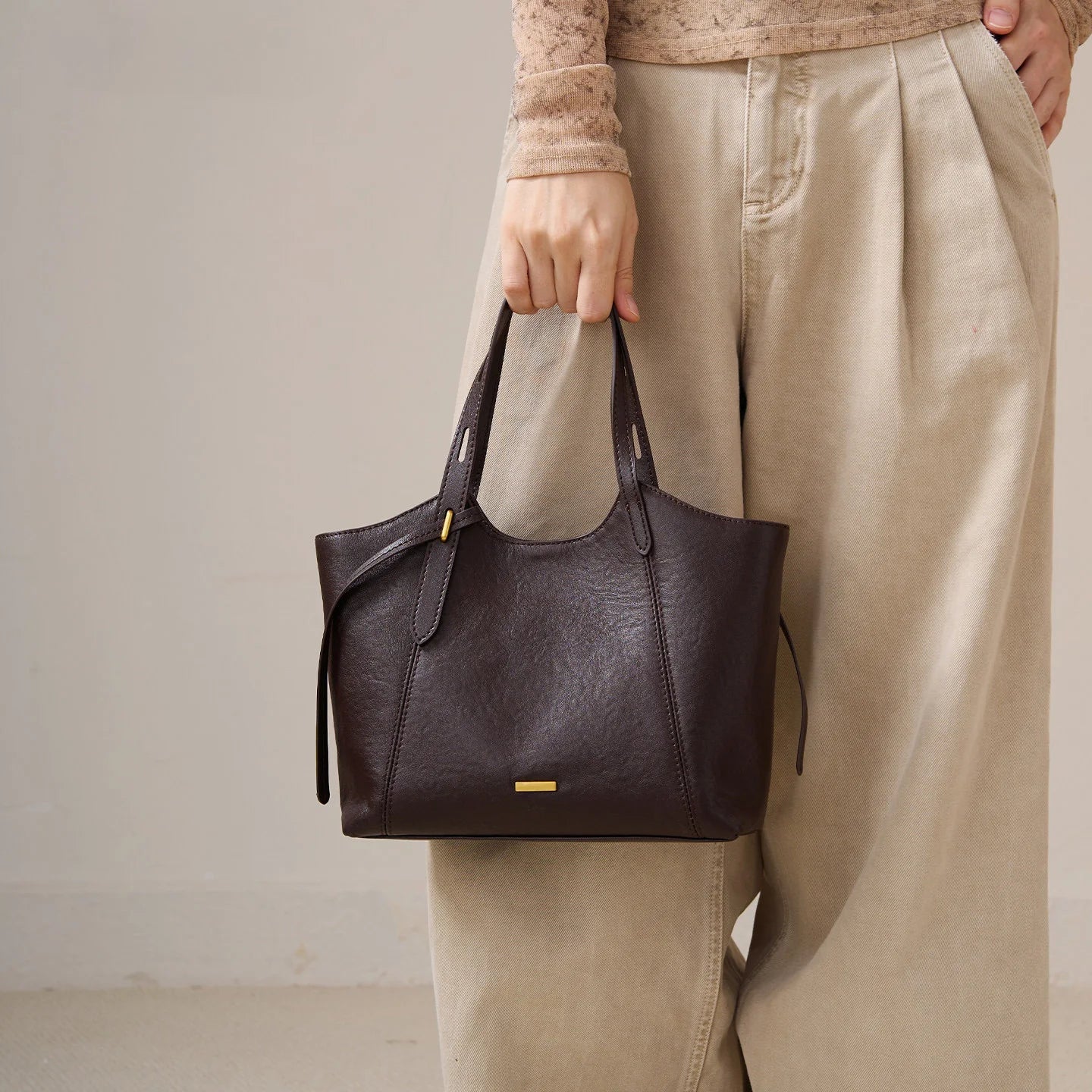 Dark brown genuine top grain leather designer handbag with minimalist gold hardware and double shoulder straps.