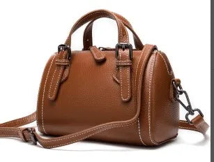 Brown genuine leather designer handbag, barrel-style shoulder tote with buckle strap details and contrast stitching.