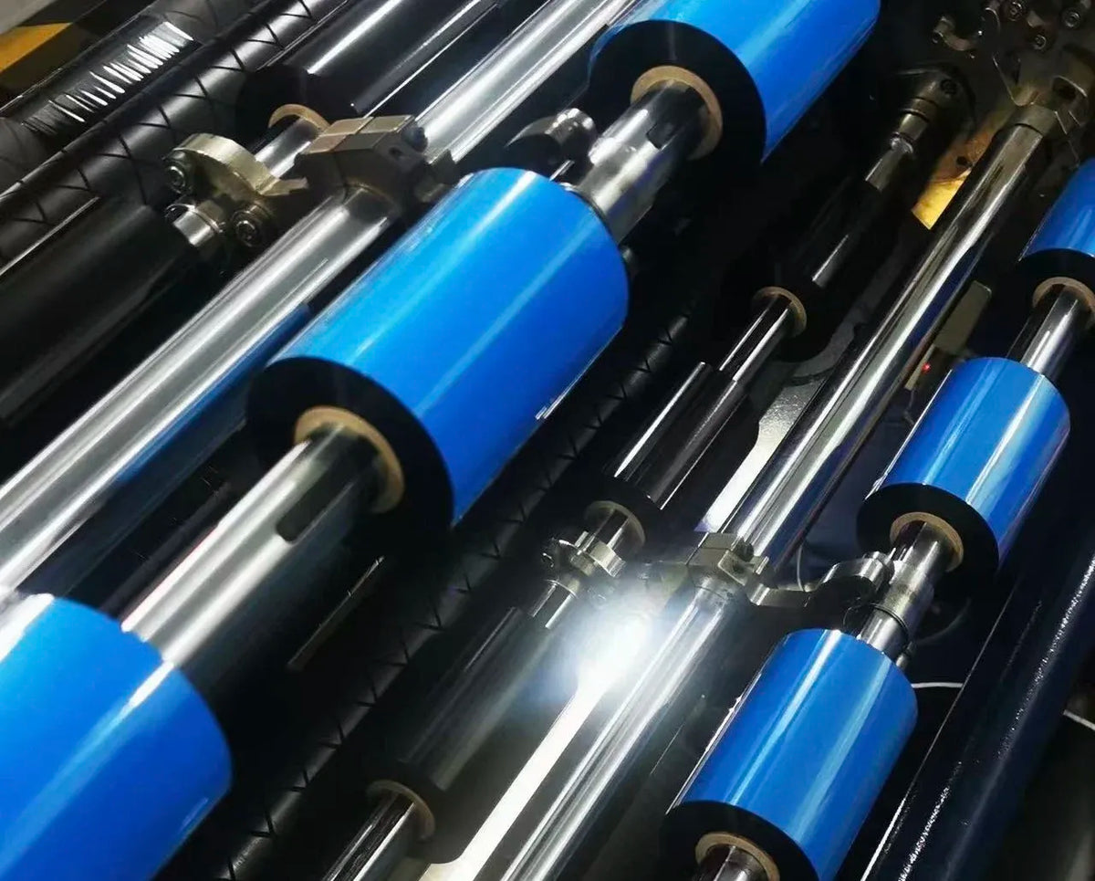 Thermal transfer ribbon spools close-up, black tape rolls on blue and silver shafts