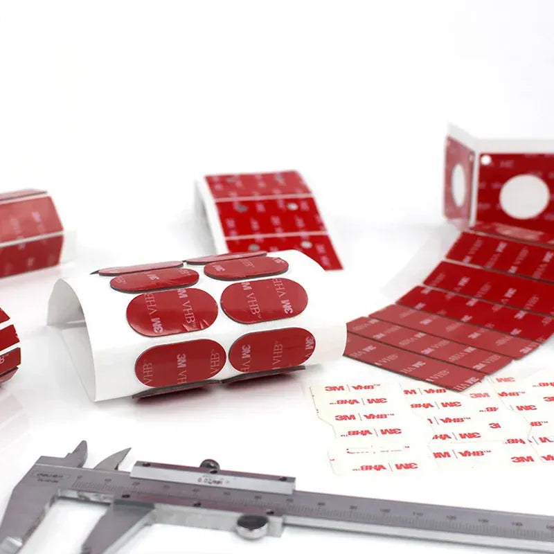 Red die-cut double-sided acrylic foam tape pads on release backing, circles and rectangles