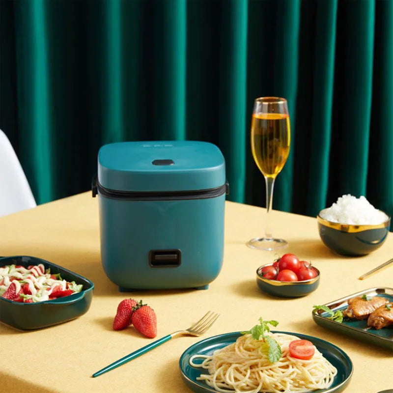 Teal mini electric rice cooker with power switch and tabletop meal accessories