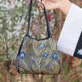 Black designer handbag with gold peacock feather Su embroidery and blue accents for daily use.