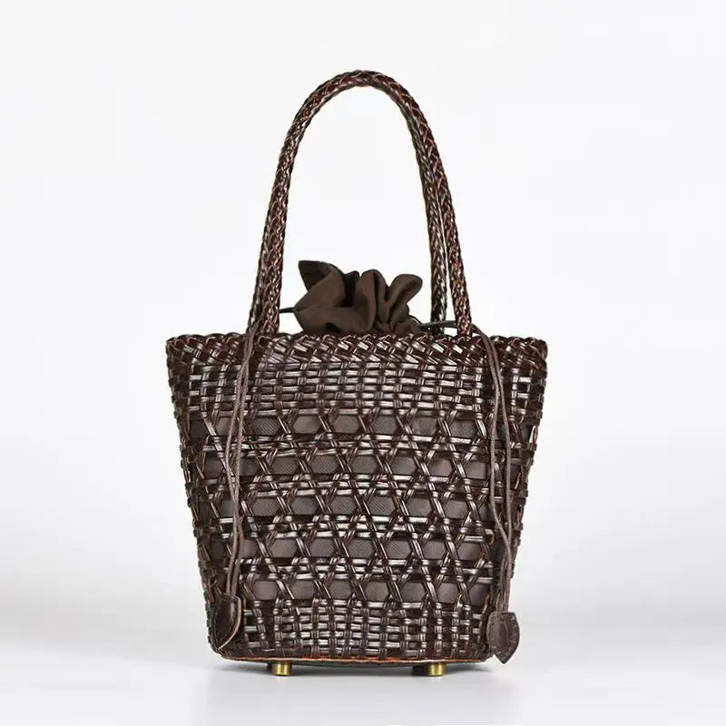 Dark brown handwoven leather bucket tote with cross-weave cannage design, braided handles, and drawstring pouch.