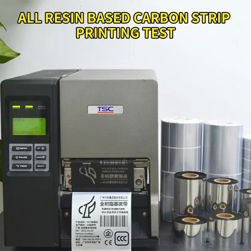 Thermal transfer ribbon rolls beside label printer, silver foil with black cores