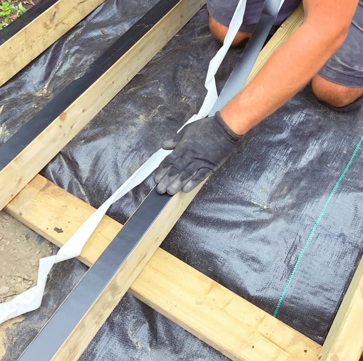 Black tape laid across parallel wooden beams with trimmed edges and alignment