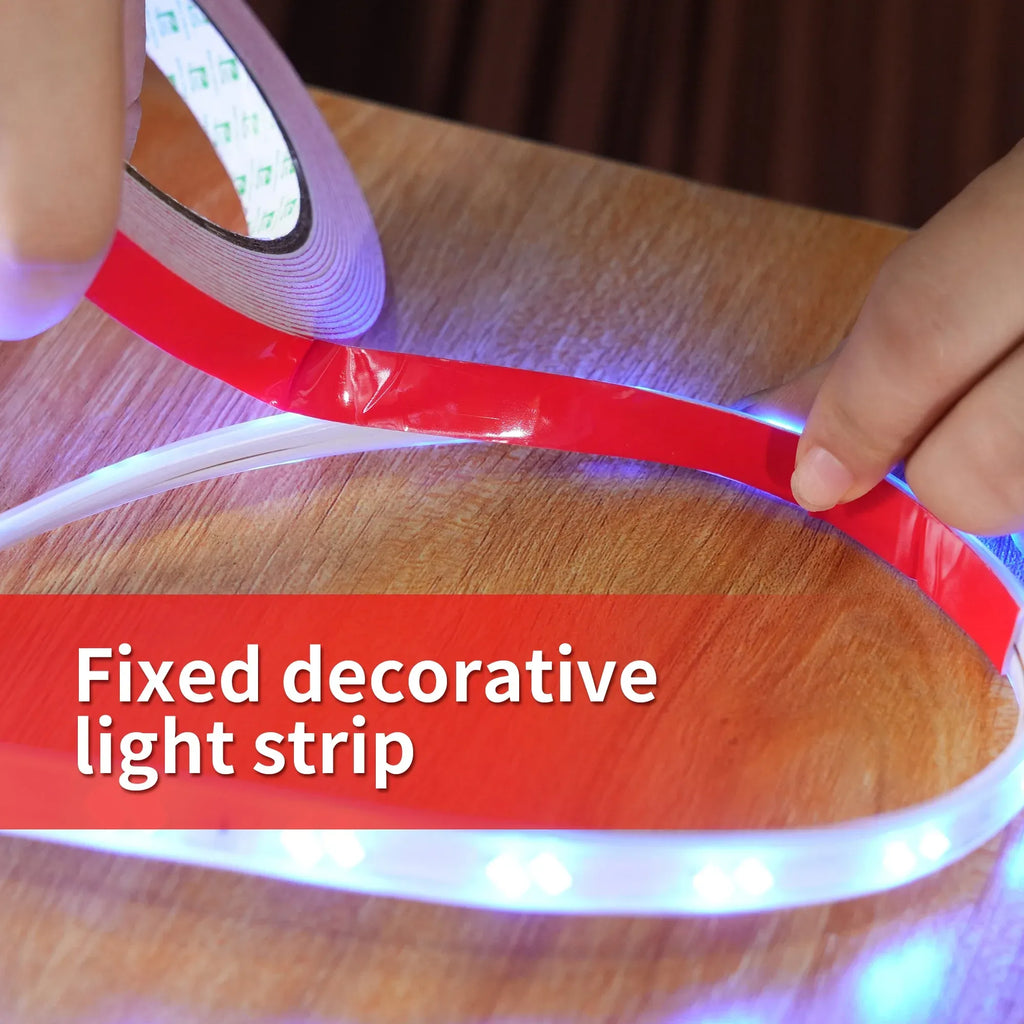 Red double-sided foam tape fixing a decorative light strip on wood surface