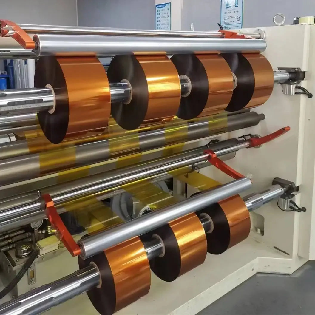 Amber-gold tape rolls on industrial machine unwind, dark adhesive side rings