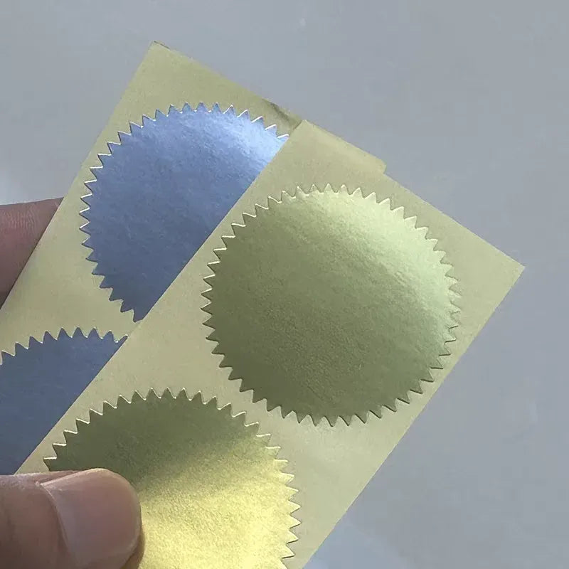 Shiny gold round stickers with scalloped edges on backing sheet, close-up