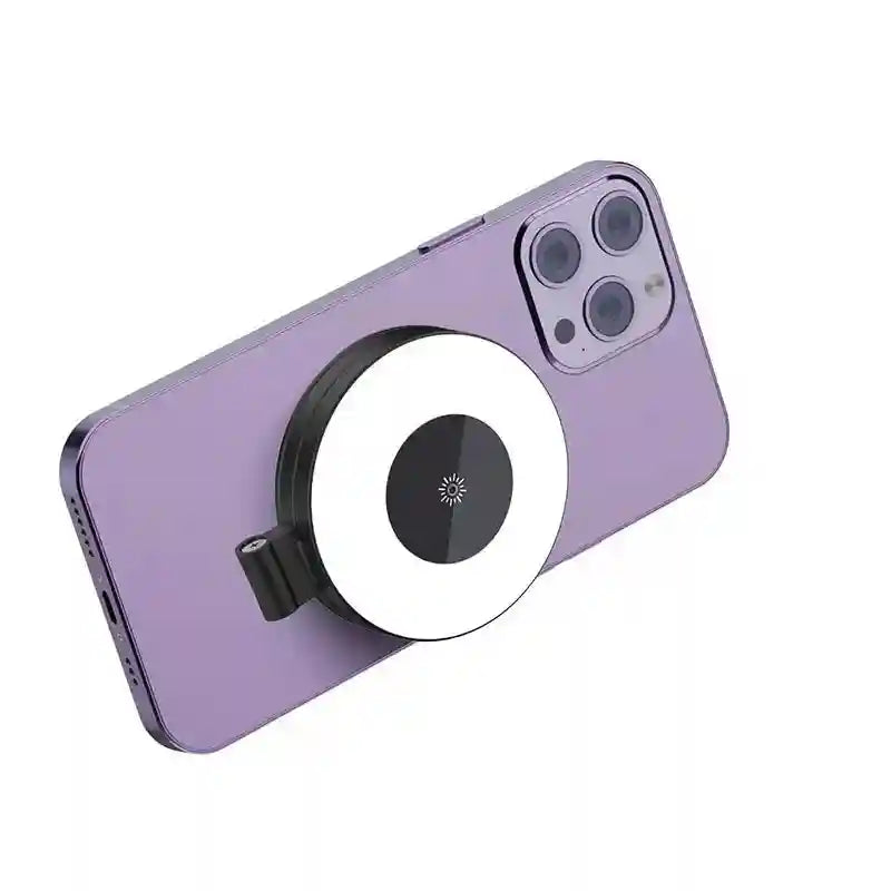 Circular black and white magnetic selfie ring light attached to the back of a purple smartphone for illumination.