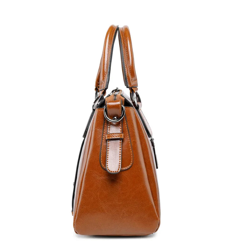 Brown cow split leather designer handbag, side view of top-handle satchel with dual handles and metal ring hardware.