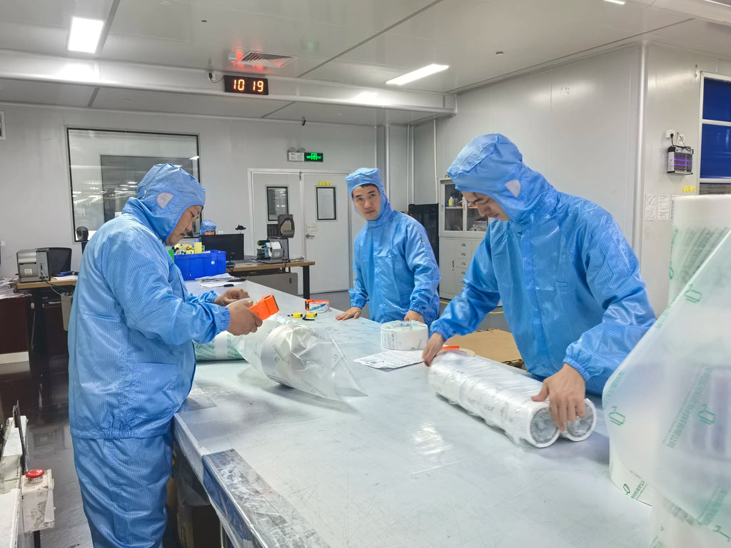 Healthcare workers in blue suits packaging rolled tape on a lab bench