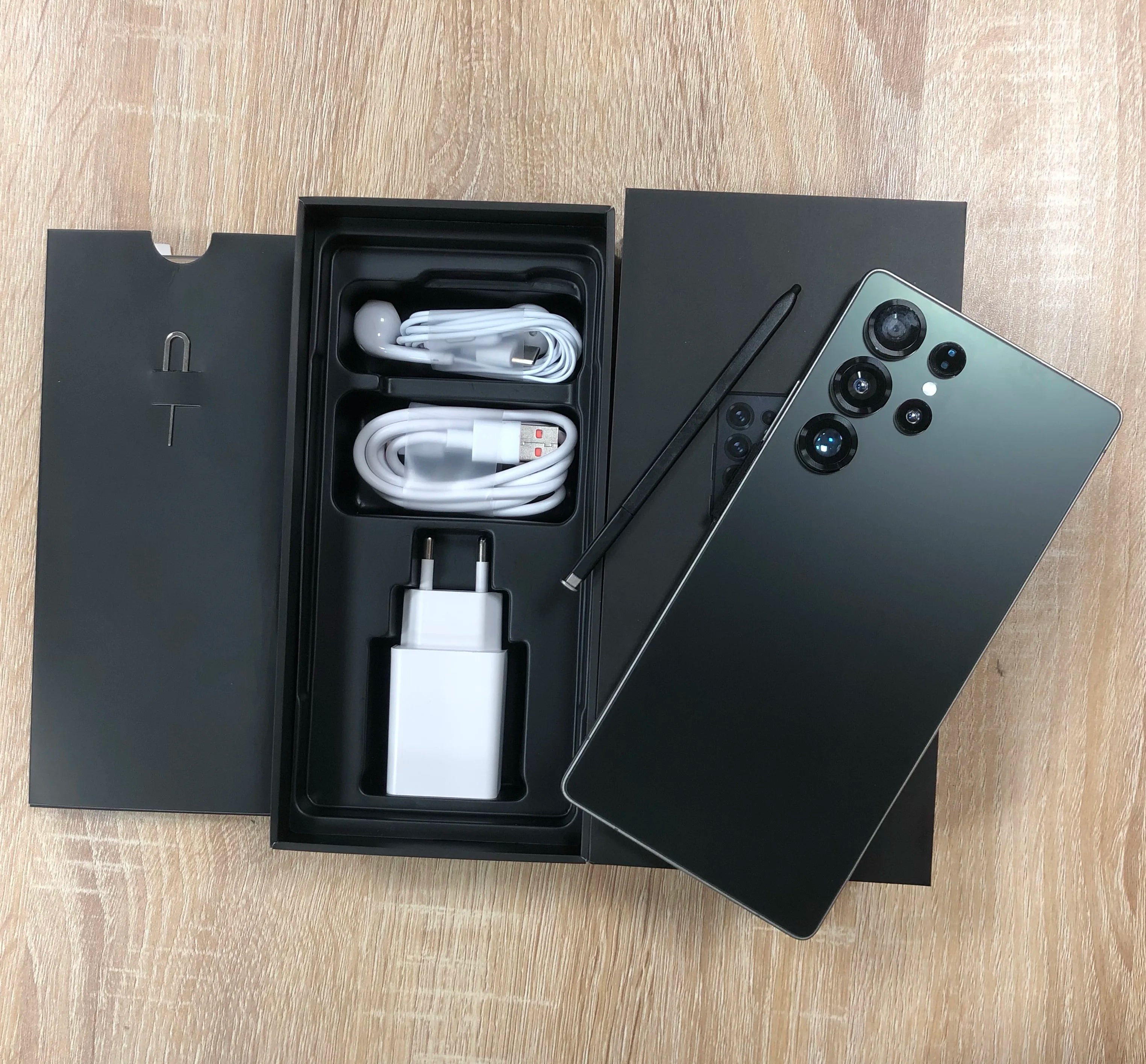 Android smartphone with dark green back and quad rear cameras; box includes cable and charger