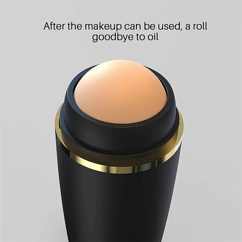 Close-up of a matte black oil-absorbing roller with a round, beige volcanic stone tip and a gold-rimmed neck.