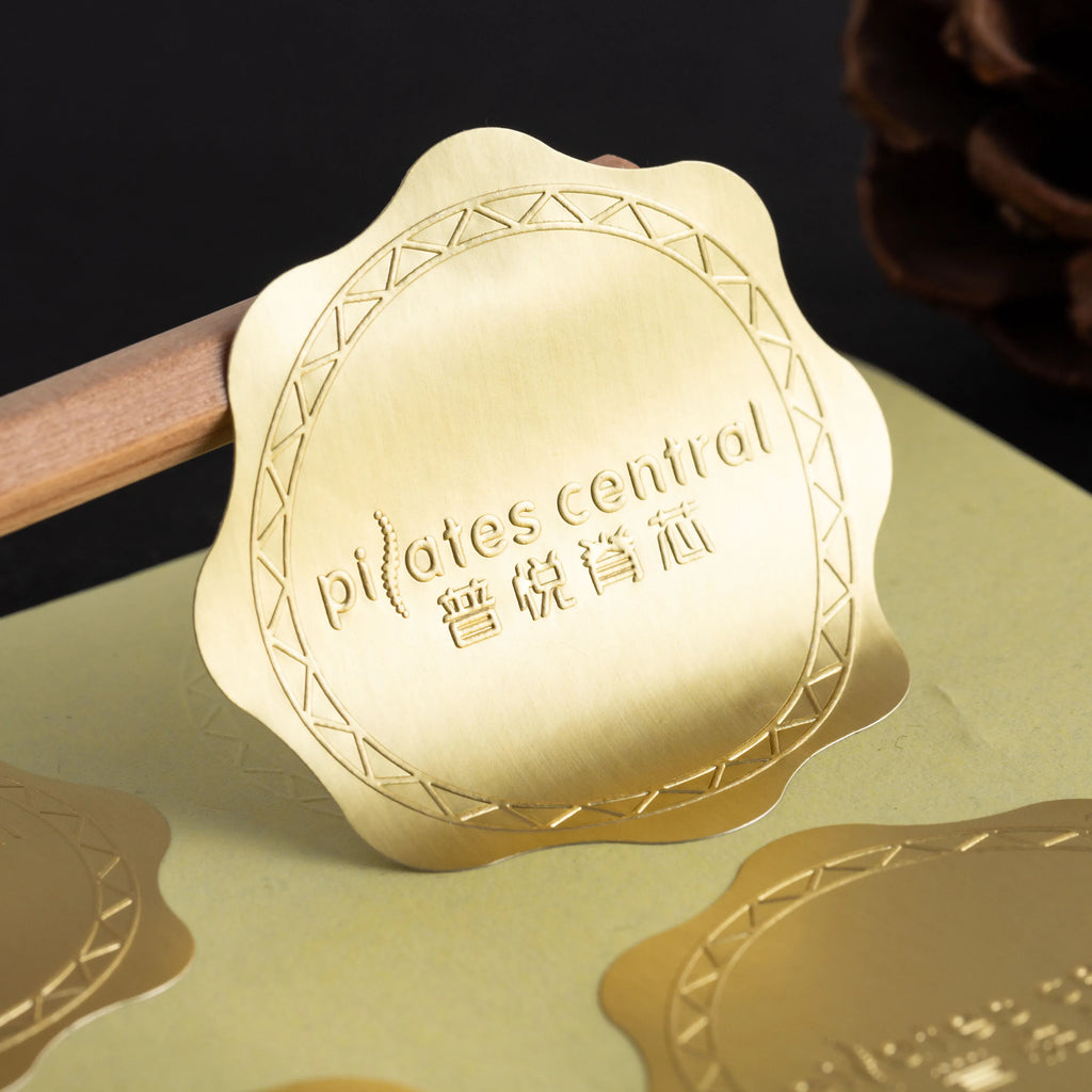 Gold heart-shaped sticker with embossed border and script text on backing sheet