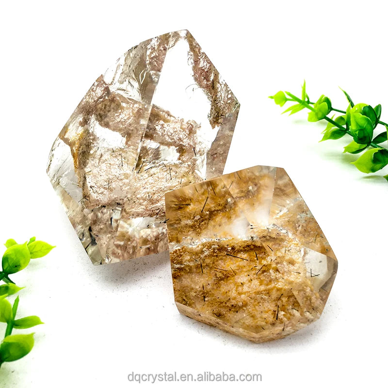 Two polished phantom quartz crystals, clear with golden-brown inner veining and facets