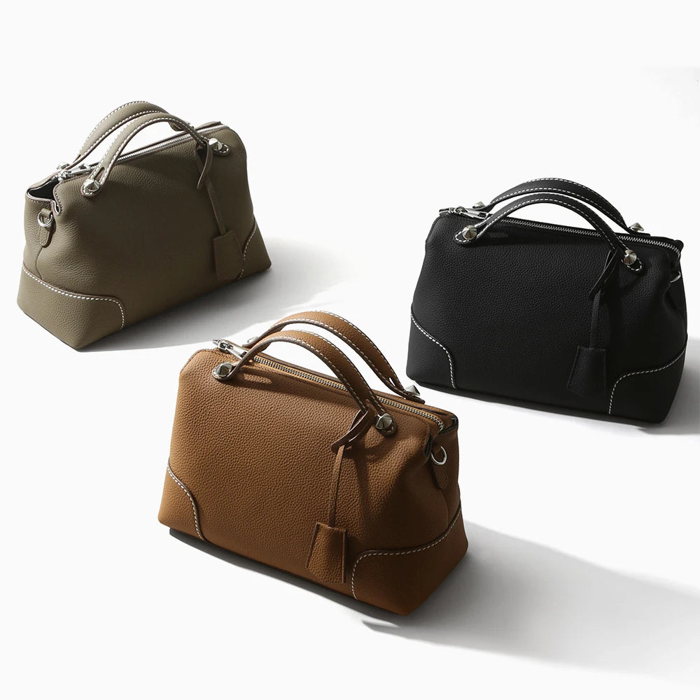 Designer handbags in black, brown, and olive top-grain cowhide leather with white stitching and silver hardware.