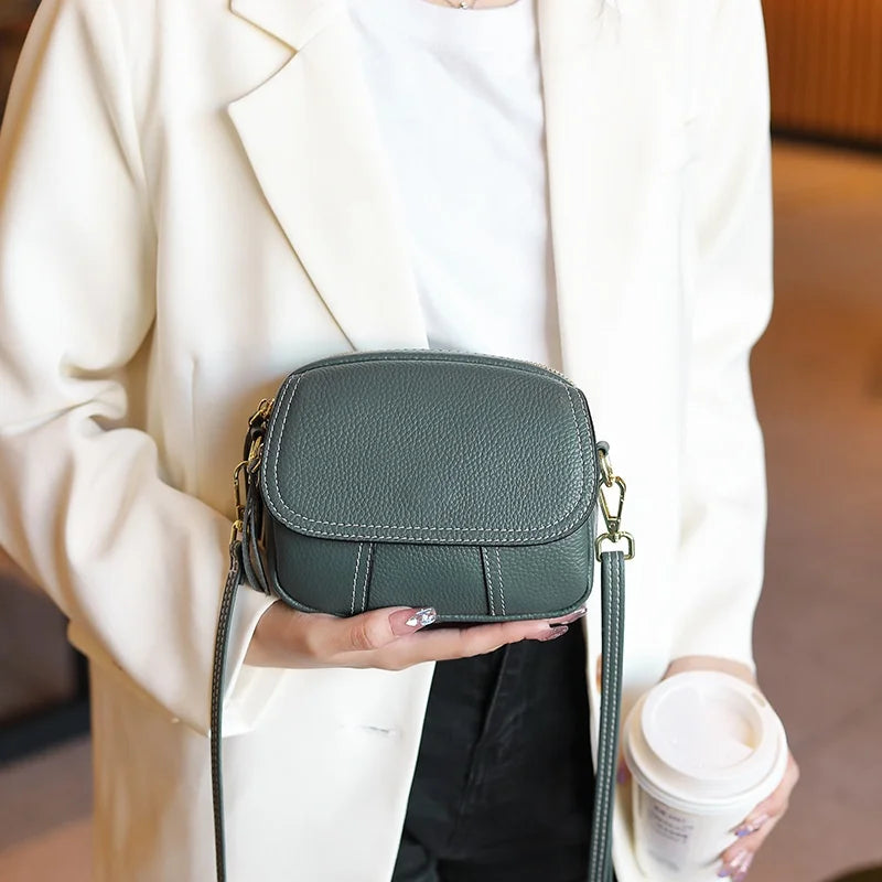 Green genuine leather designer crossbody bag with white stitching and zipper closure for women.