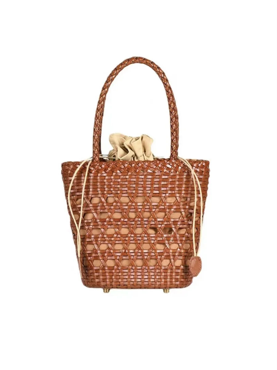 Tan handwoven leather bucket tote with cross-weave cannage design, braided handle, and drawstring interior lining.