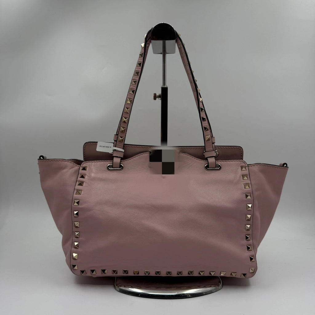 Pale pink leather designer shoulder bag with silver pyramid rivets on straps and trim. Wholesale luxury handbag.