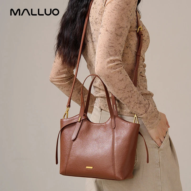 Luxury brown top-grain leather designer handbag with adjustable shoulder strap and minimalist gold-tone hardware.