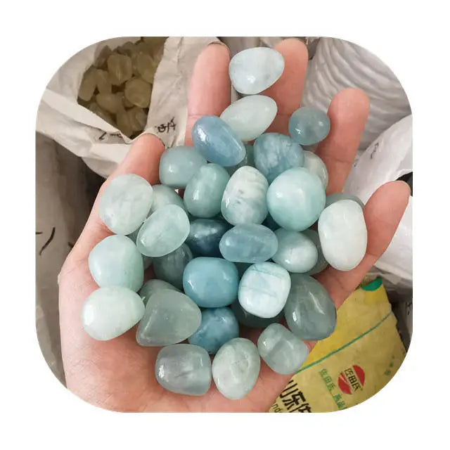 Tumbled sky-blue aquamarine crystals in a palm, assorted pale blues and white stones