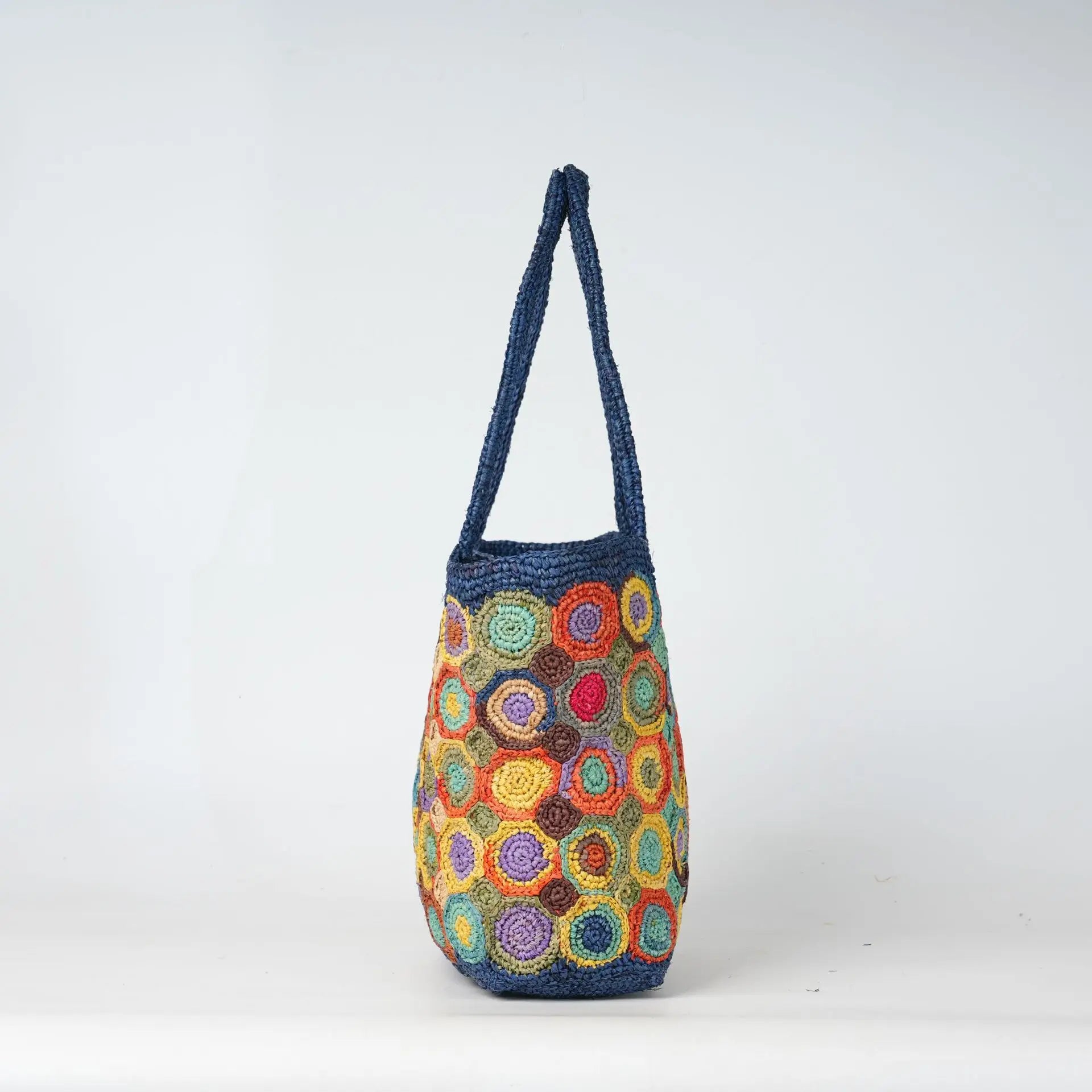 Blue crochet beach tote bag featuring a colorful circular woven pattern and durable handle for summer fashion.