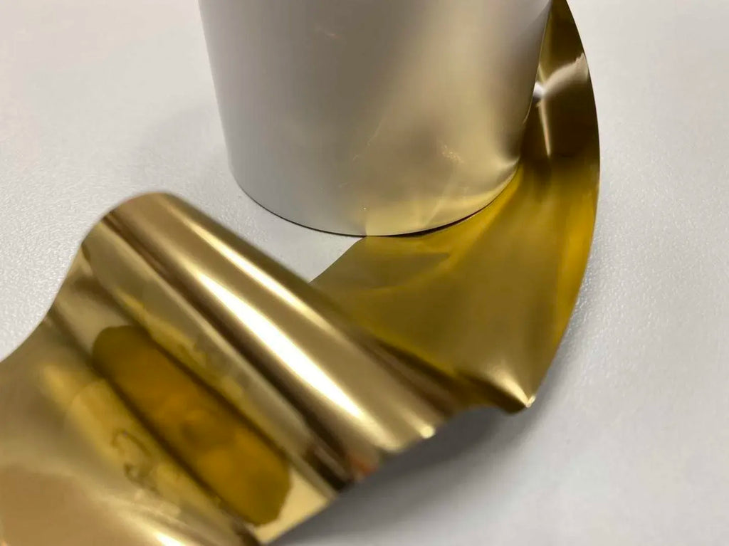 Shiny gold metallic thermal transfer ribbon foil, loosely wound from a roll on core