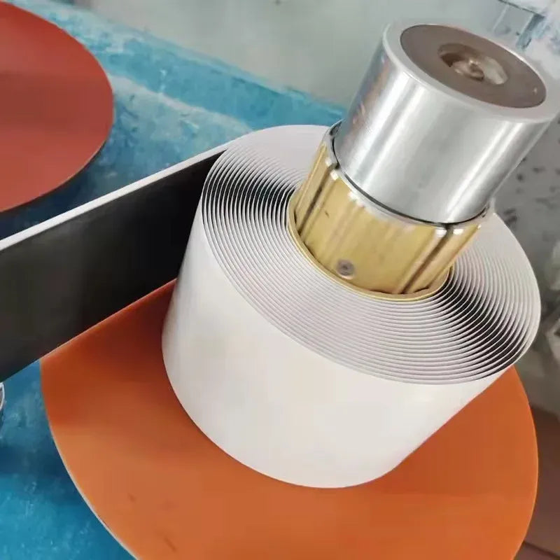 White and silver-gray sealant tape with foil backing around a roll applicator