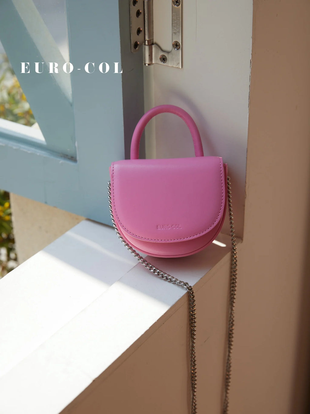 Small pink cowhide leather evening clutch with a top handle and silver chain strap. Designer party handbag.