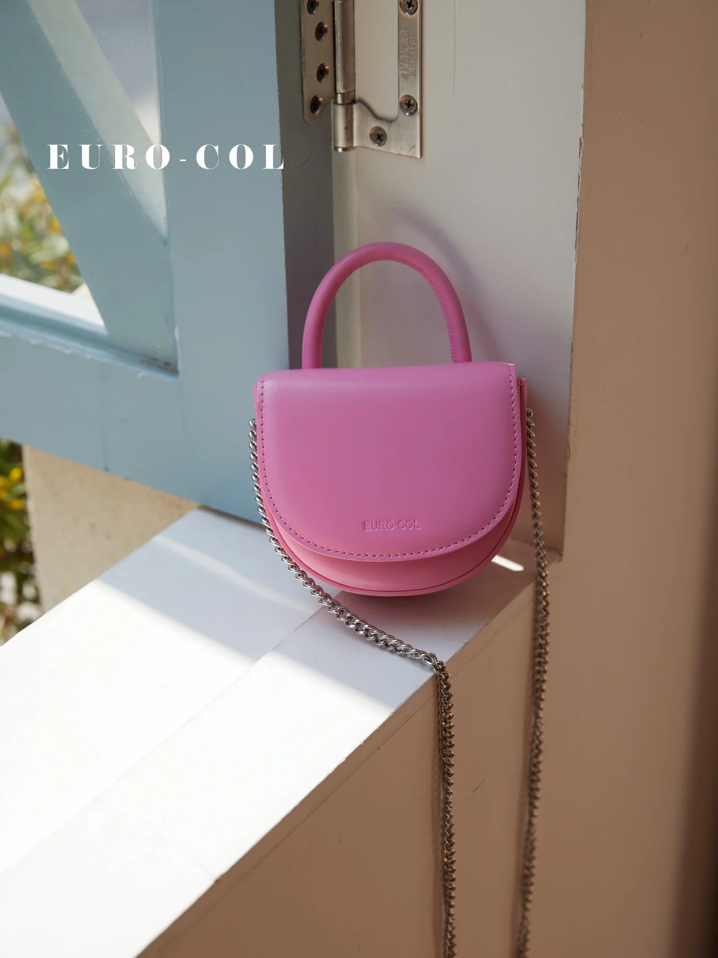 Small pink cowhide leather evening clutch with a top handle and silver chain strap. Designer party handbag.