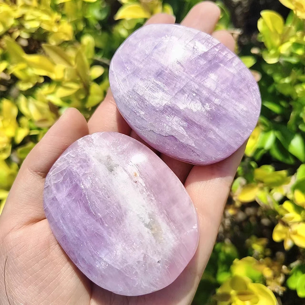 Two Kunzite palm stones, lavender-purple oval polished stones in hand