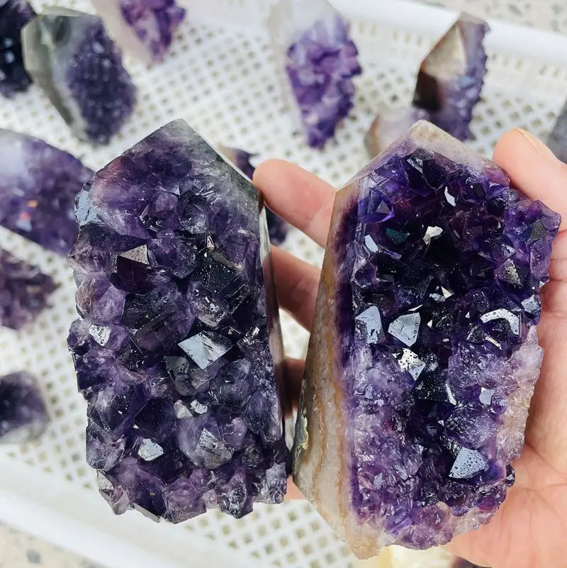 Two purple amethyst geode crystal clusters held in hands
