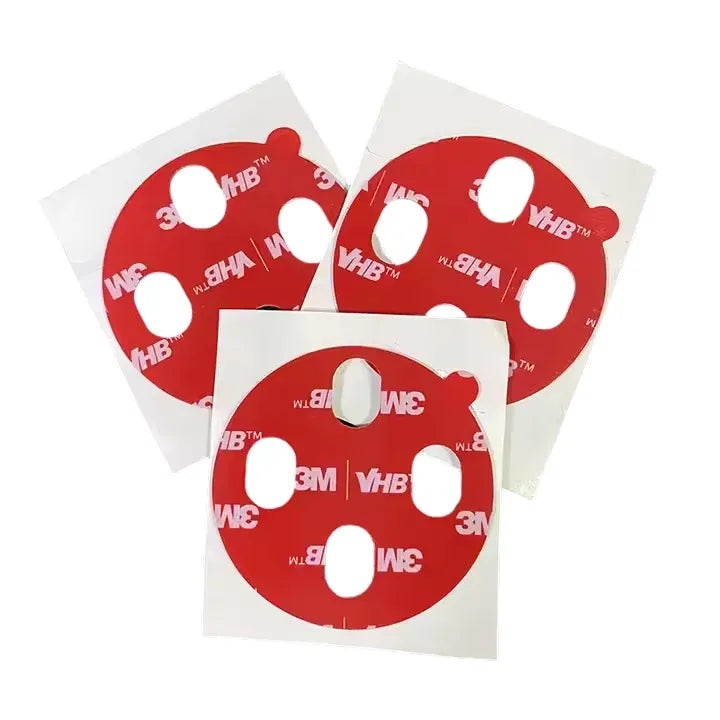 Round die-cut foam tape pieces with center holes on red backing sheets