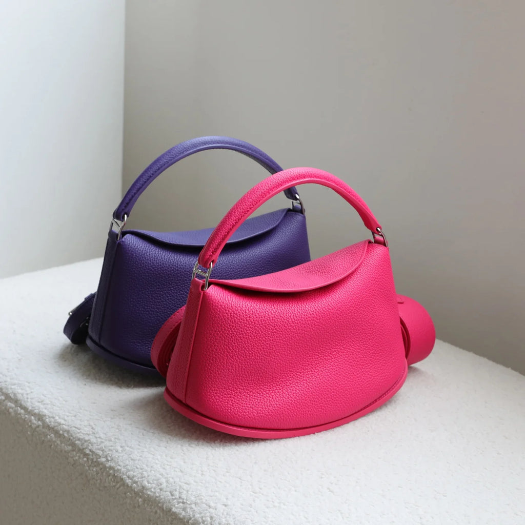 Pink and purple pebble-grain cowhide leather pillow handbags with top handles and magnetic closures. Designer style.