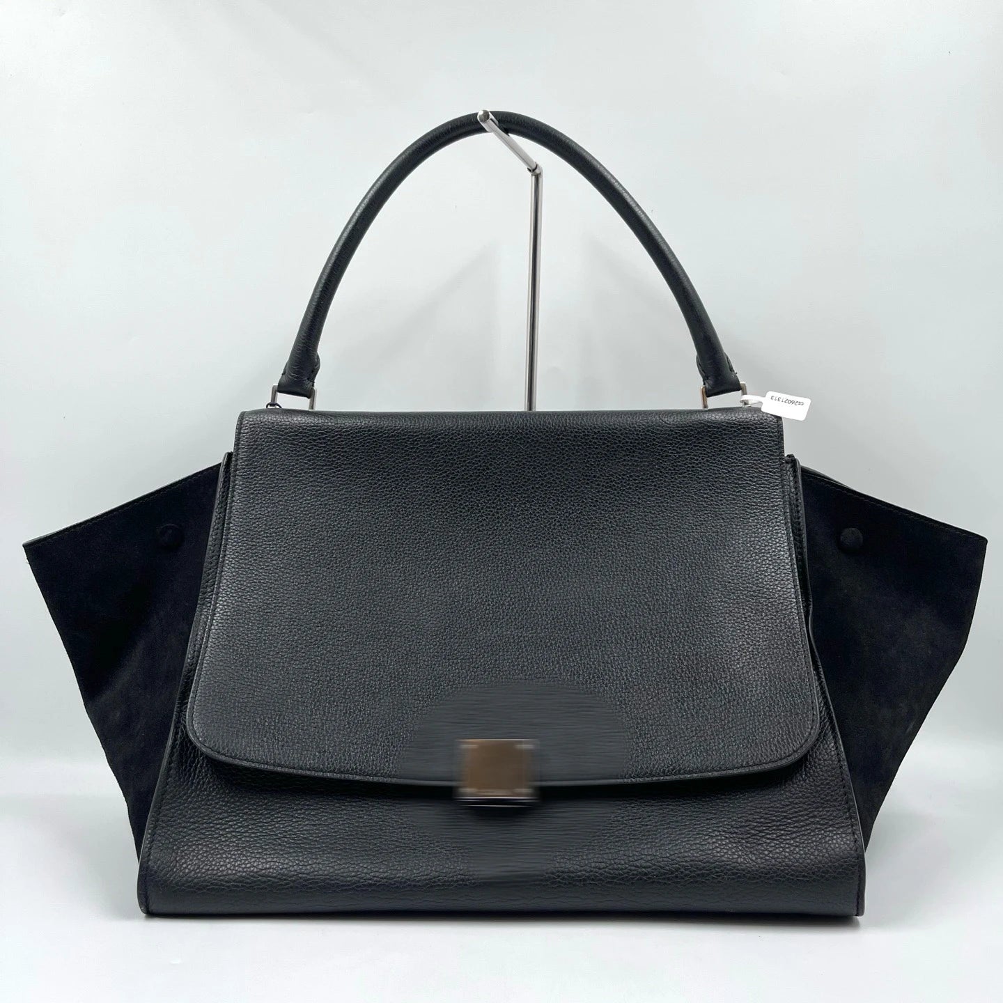Classic black designer shoulder bag in lychee texture leather with vintage swing side panels and a single top handle.