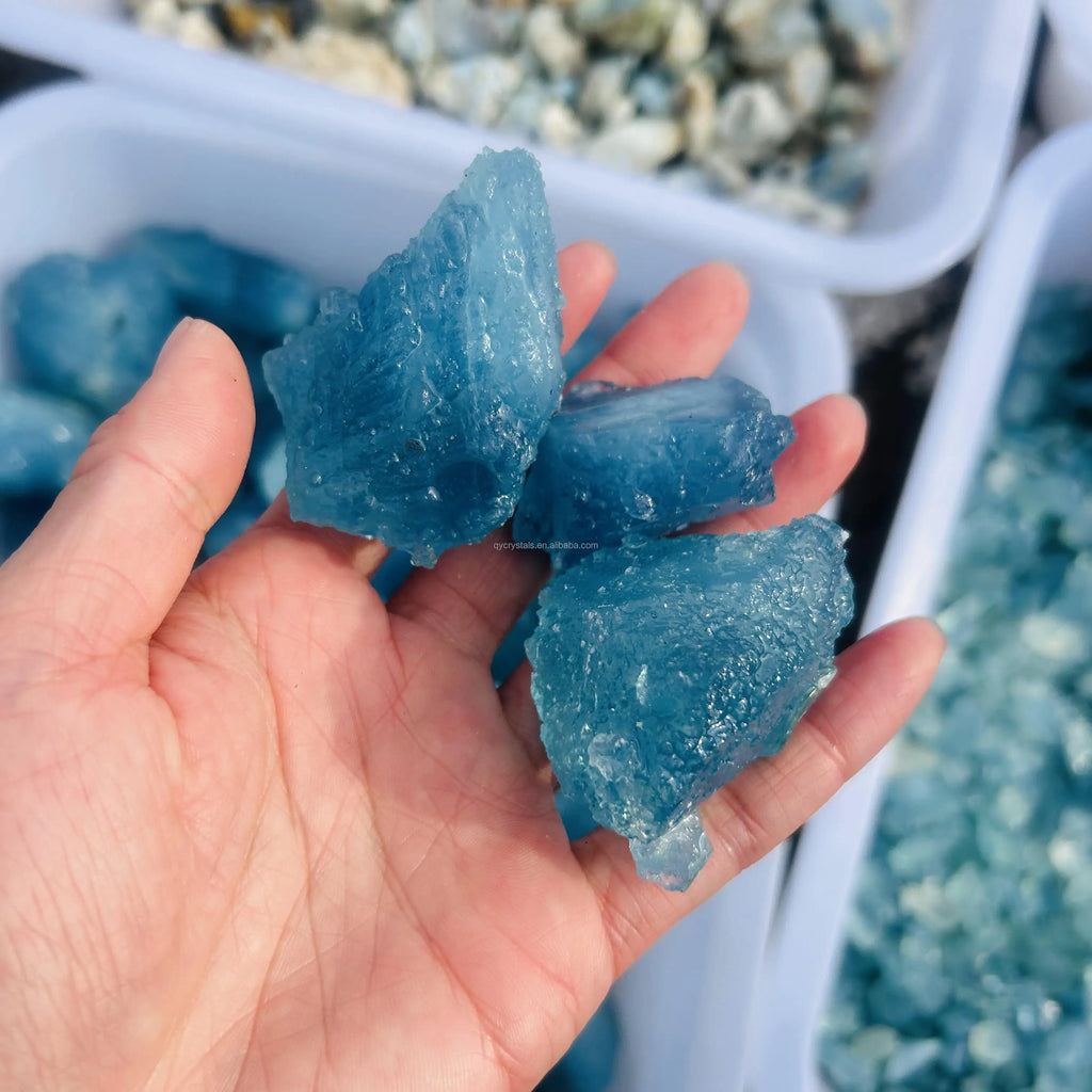 Three sky blue aquamarine rough crystal stones, jagged pieces in hand