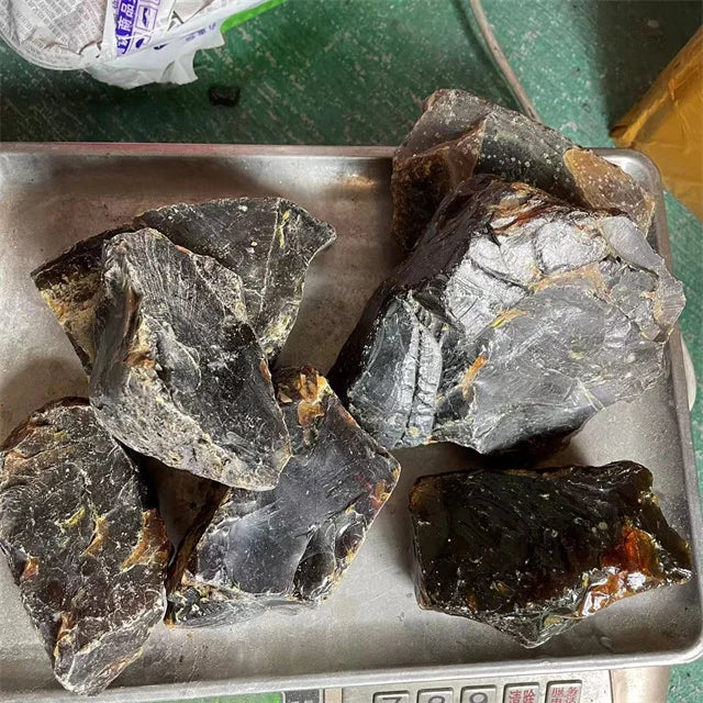 Assorted rough amber gemstone pieces in a metal tray