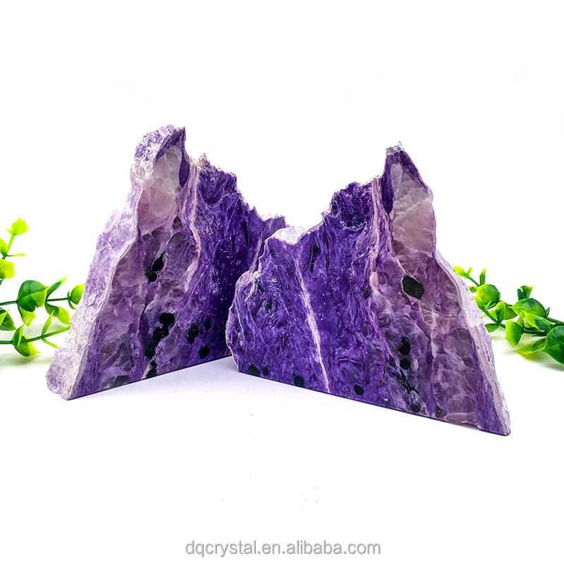 Pair of polished purple charoite slice stones, pointed arch-like shapes with dark spots