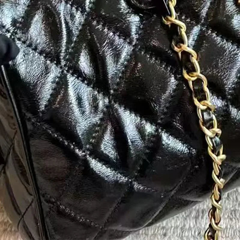 Black shiny quilted designer barrel handbag with gold chain strap, featuring a sophisticated diamond-stitched texture.