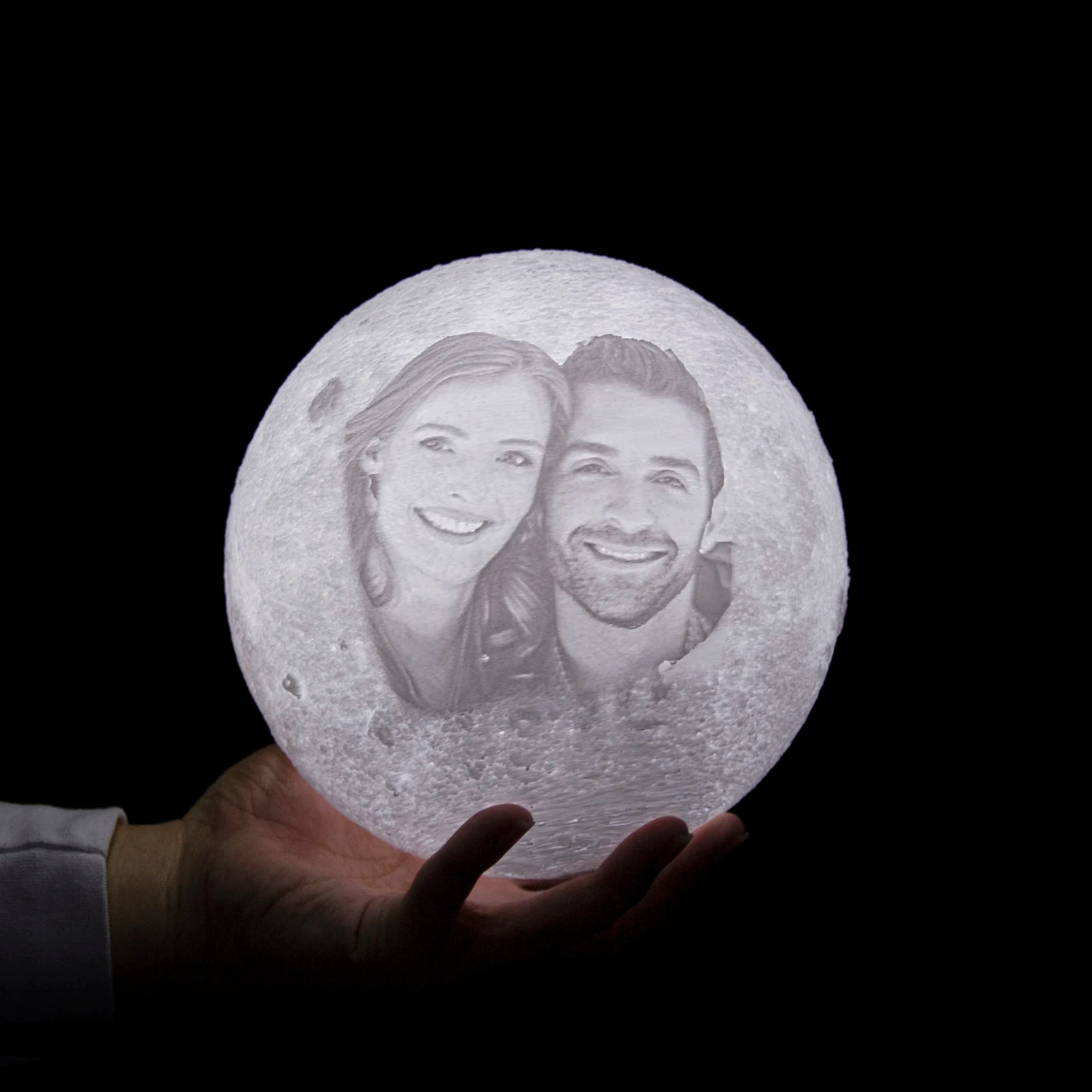 Custom moon lamp with a 3D-printed photo of a couple, textured white surface, glowing on a hand against black.