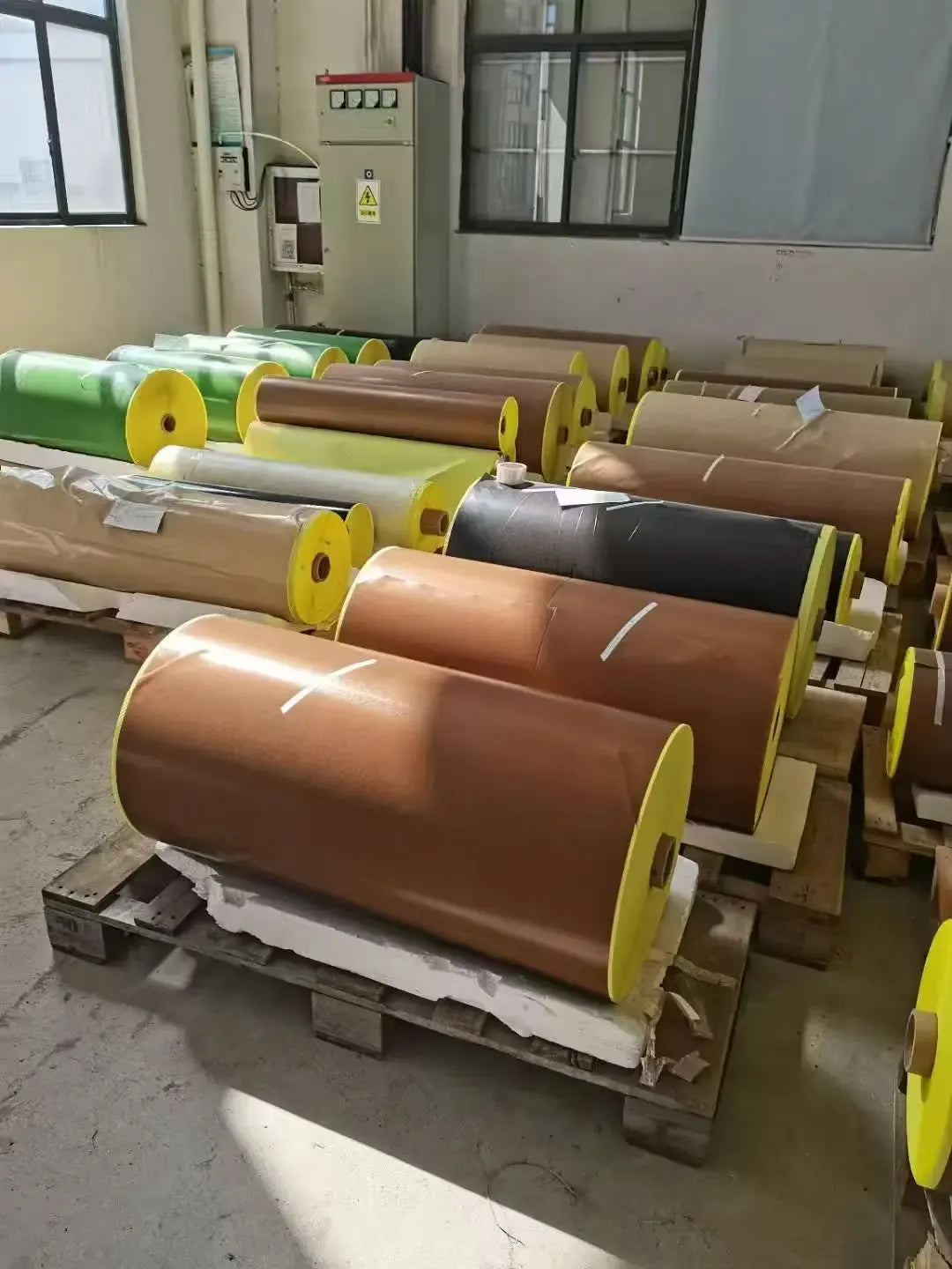 Large brown tape rolls mounted on yellow holders in a workshop