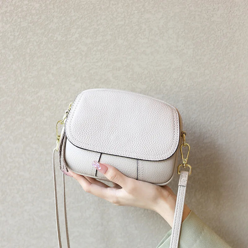 Beige pebble leather mini designer handbag with gold hardware, detachable strap, and classic underarm crossbody style.