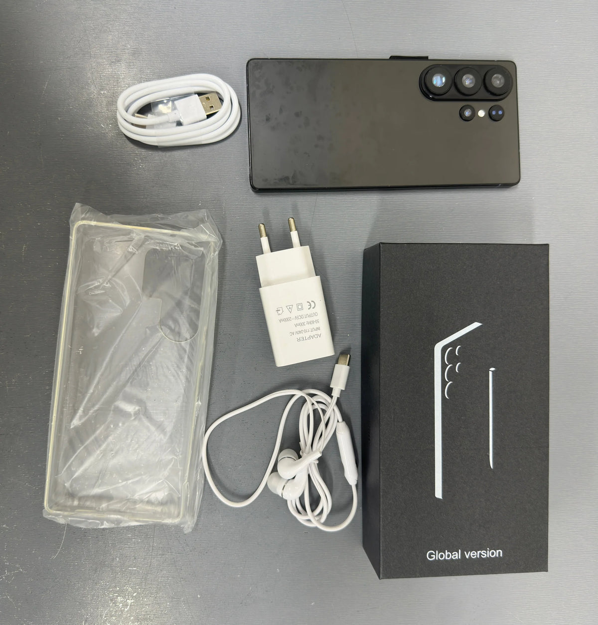Gray smartphone with quad cameras and included charger, cable, and protective case