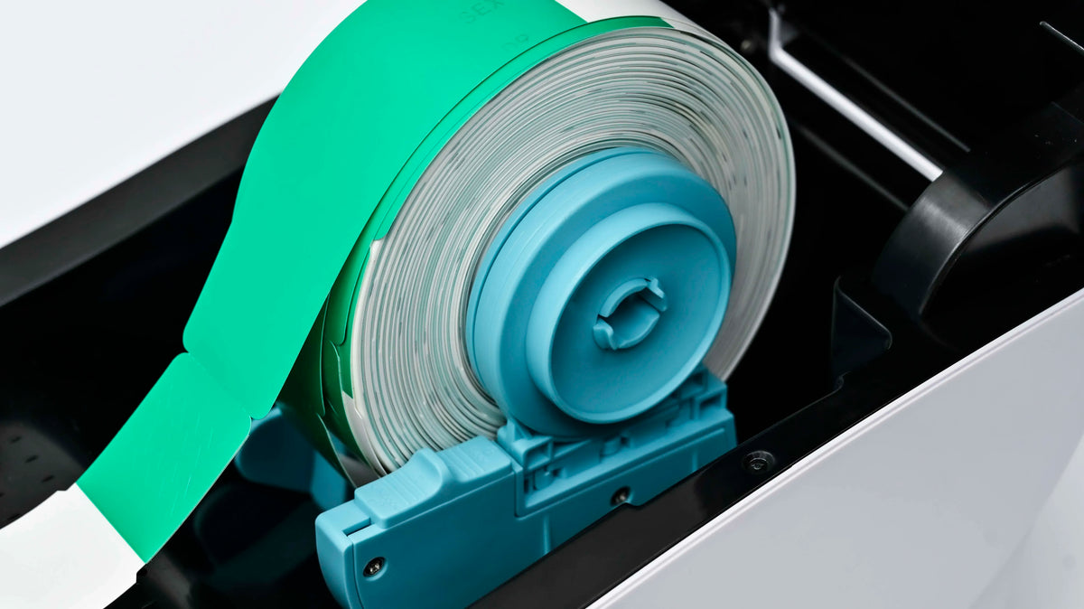 Close-up of direct thermal printer label feed with green strap and blue roller